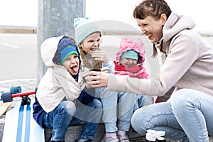 Mom pours hot tea from a thermos for three children. The kids skated on a skate board and froze.