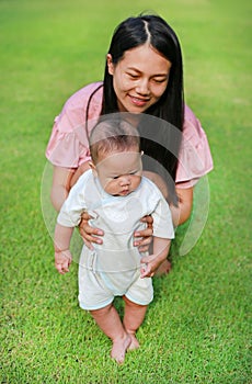 Mom practiced her baby boy first step walking on green grass garden photo