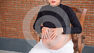 Mom pregnant woman in a dress holds hands on belly on red brick background, Waiting for the birth of your baby with love