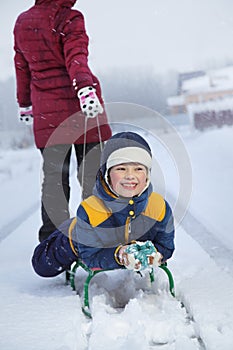 Mom pulls a sled with his son on snowy road