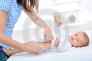 Mom puts on diaper baby changing table