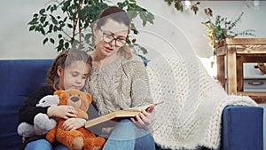 mom read a book to her daughter at home. kid dream coronavirus stay home concept. mom lockdown is sitting on the couch