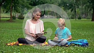 Mom reading book, son using tablet, alternative education with IT technologies