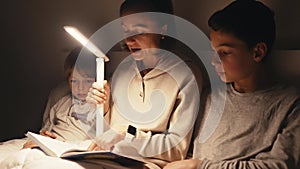 Mom reading book to children. Mother and children at night in bedroom and reading book before bed.