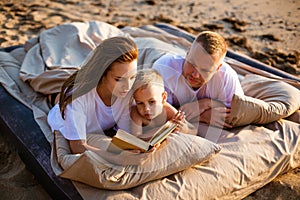 Mom is reading a book to her son while lying on the bed.