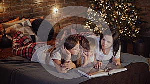 Mom reads a book to children in the bedroom