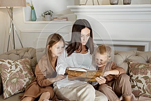 Mom reads a book to the children. A woman tells a story to a boy and a girl before going to bed. Mom daughter and son relax