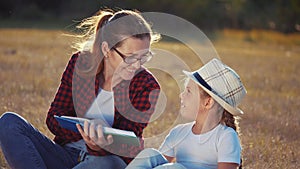 Mom reads a book to her daughter in the park on vacation. Happy family kid dream concept. Mother reads a book to his