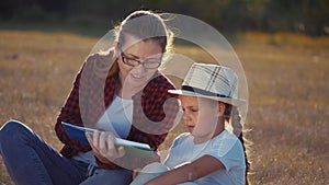 Mom reads a book to her daughter in the park on vacation. happy family kid dream concept. mother reads a book to his