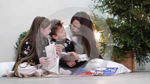 Mom reads a fairy tale to children before bed on New Year's Eve. Happy family on New Year's Eve