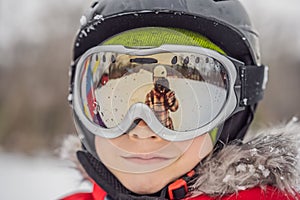 Mom reflected in the boy ski goggles. Mom and Dad teach a boy to ski or snowboard