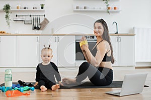 Mom with resistance band training near baby on room floor