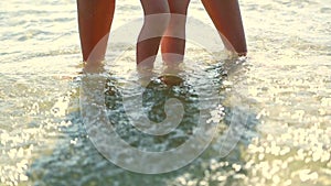 Mom`s feet with baby in the sea. Wave washes children`s legs