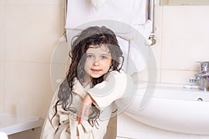 Mom`s hands are washed kid hair with shampoo in the bathroom. Portrait of a beautiful brunette little girl with wet hair, blue eye