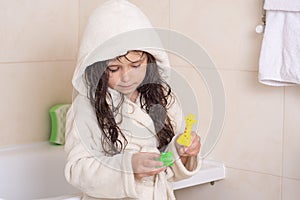 Mom`s hands are washed kid hair with shampoo in the bathroom. Portrait of a beautiful brunette little girl with wet hair, blue eye