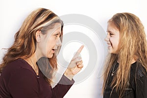 Mom scolding her daughter with an angry face and waves her finger on a white background. Daughter at the same time just smiles