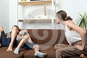 Mom scolds the sons who are lying on couch and lounging around. Raising teenage sons. Mom scolds children