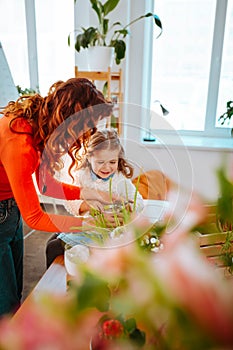 Mom showing her little daughter how to take care of plants