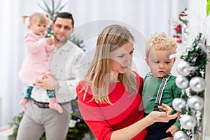 Mom shows her little son the Christmas baubles on the wreath