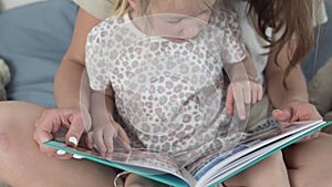 Mom shows little daughter family photos in a beautiful photo album