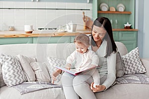 Mom sits on a sofa with a child, reads a book and looks at bright pictures