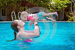 Mom with a small child of eight months having fun and swimming in the pool. Summer vacation at sea. A woman kisses her baby