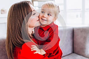 Mom smiles and kisses her daughter. A happy family. Portrait of a mother.