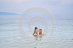 Mom and son Asians bathe in the sea - mother holds the child