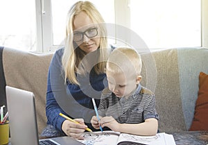 Mom and son do their homework, study online on the Internet. The concept of preschool education,home schooling of quarantined photo
