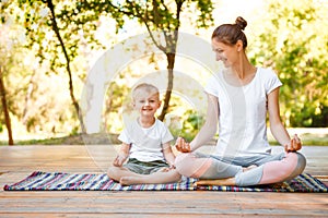 Mom and son do yoga in a summer park. Healthy lifestyle.