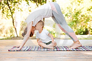 Mom and son do yoga in a summer park. Healthy lifestyle.