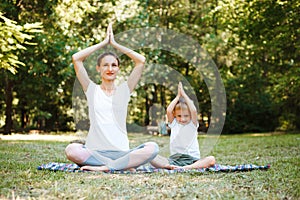 Mom and son do yoga in a summer park. Healthy lifestyle.