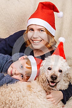 Mom, son and dog in New Year`s hats are smiling during the Christmas holidays. Happy family having fun