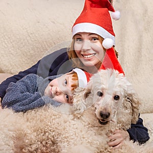 Mom, son and dog in New Year's hats are smiling during the Christmas holidays. Happy family having fun