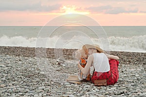 Mom and son embrace on a pebble beach. Sunset time. Back view