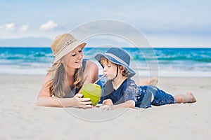 Mom and son enjoy the beach and drink coconut