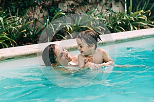 Mom an son get fun into the water in a swimming pool