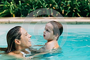 Mom an son get fun into the water in a swimming pool