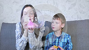 Mom and son inflate a big bubbles from a slimes. Play with slime.