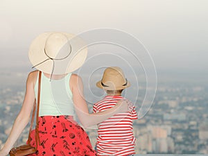 Mom and son and look at the city from a height. Rear view, evening time