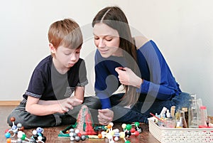 Mom and son looking at chemical reaction with gas emission. Experience with plasticine volcano at home.