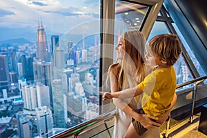 Mom and son are looking at Kuala lumpur cityscape. Panoramic view of Kuala Lumpur city skyline evening at sunset