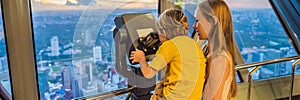 Mom and son are looking at Kuala lumpur cityscape. Use binoculars. Panoramic view of Kuala Lumpur city skyline evening