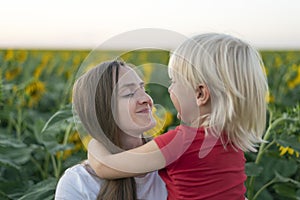 Mom and son looks each others . Portrait of happy mother and son. Sunflower field background