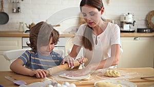 Mom, son making pastry and sitting at table in home kitchen during lockdown.
