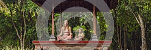 Mom and son meditate practicing yoga in the traditional balinesse gazebo BANNER, long format