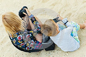 Mom and son are photographers. A woman and a young boy are holding a digital camera. Mother-child interaction, common hobby