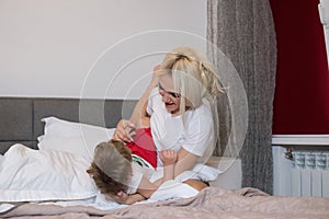 Mom and son play in the bedroom on the bed