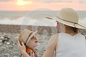 Mom and son rest on the pebble beach. Sunset time. Back view