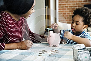 Mom and son saving money to piggy bank